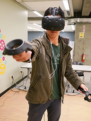 Austin Wangyu tries out a virtual reality game in Moffitt Library during a Makerspace event on April 20, 2018. (Photo by Virgie Hoban for the UC Berkeley Library)