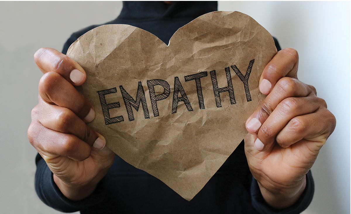 Two hands holding a paper heart that says 'empathy'