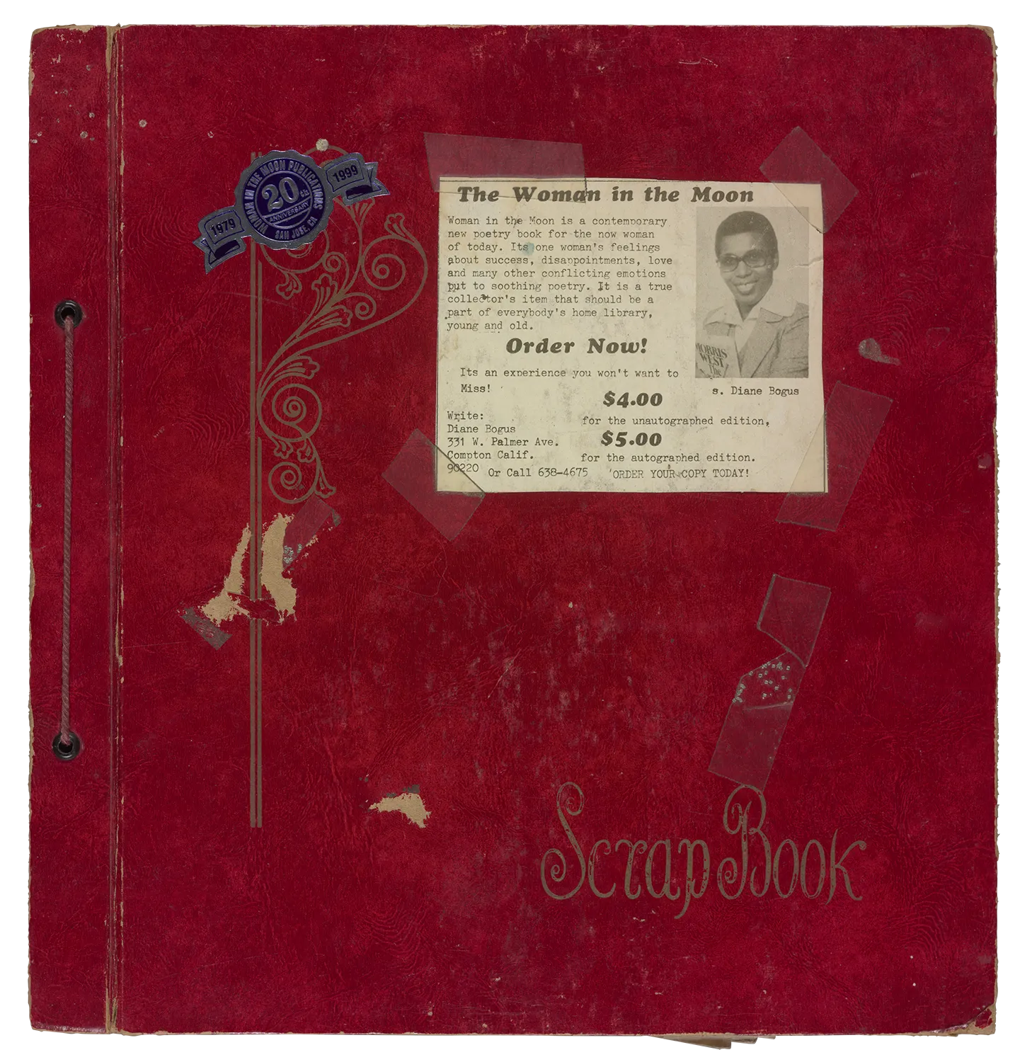 The front cover of a large red scrapbook with gold letters and embellishments. On the cover are stickers and a news clipping.